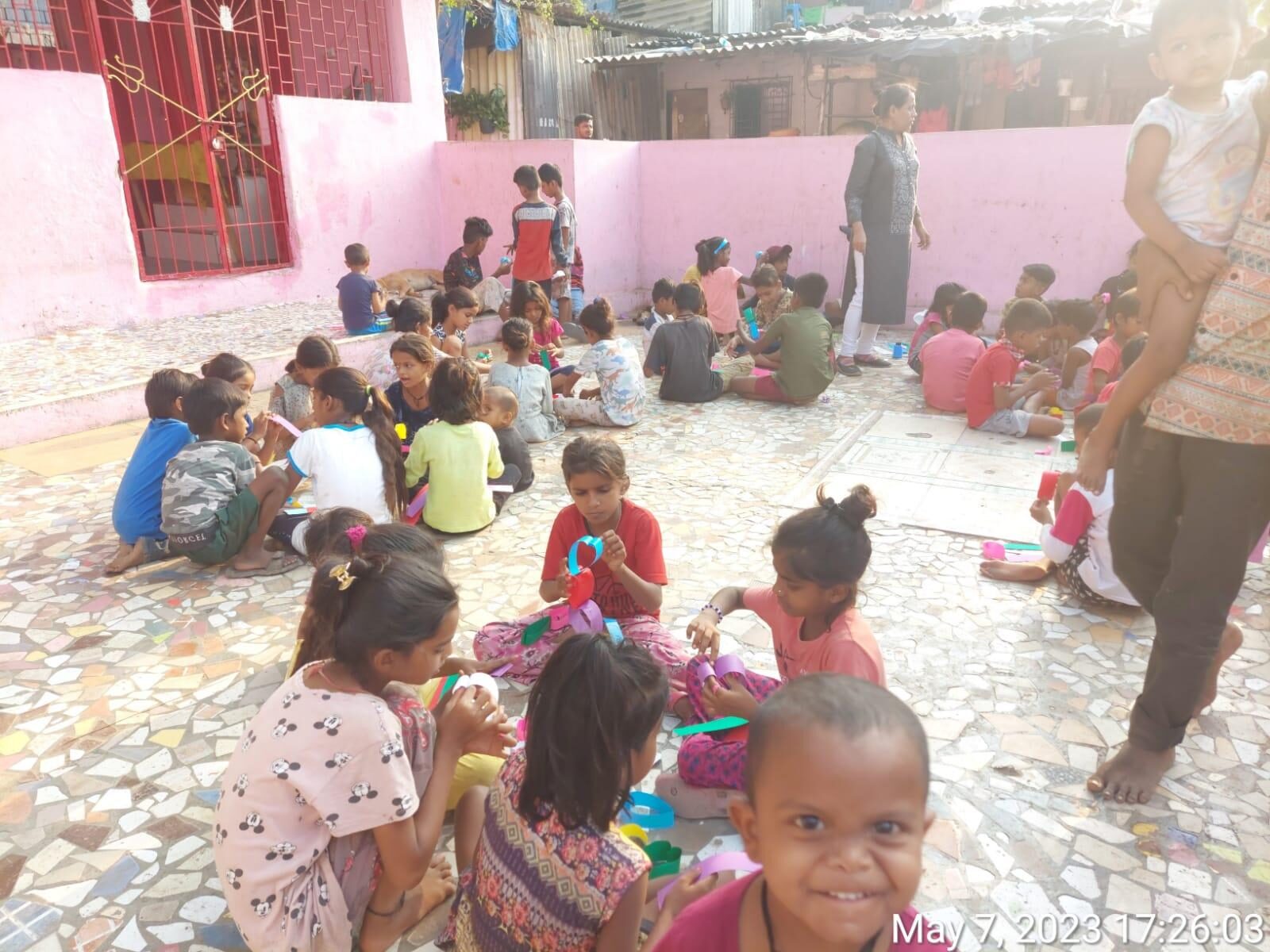 A large group of children taking part in an outdoor craft session at a Dira Foundation community courtyard